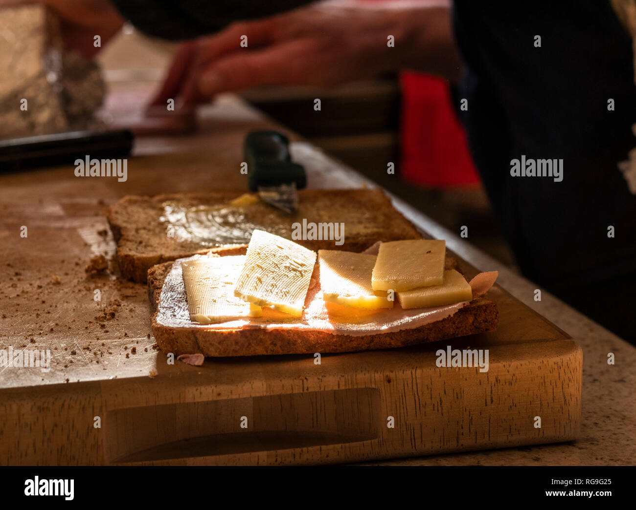 Woman making sandwiches in the kitchen. Sunlight is falling on the food Stock Photo