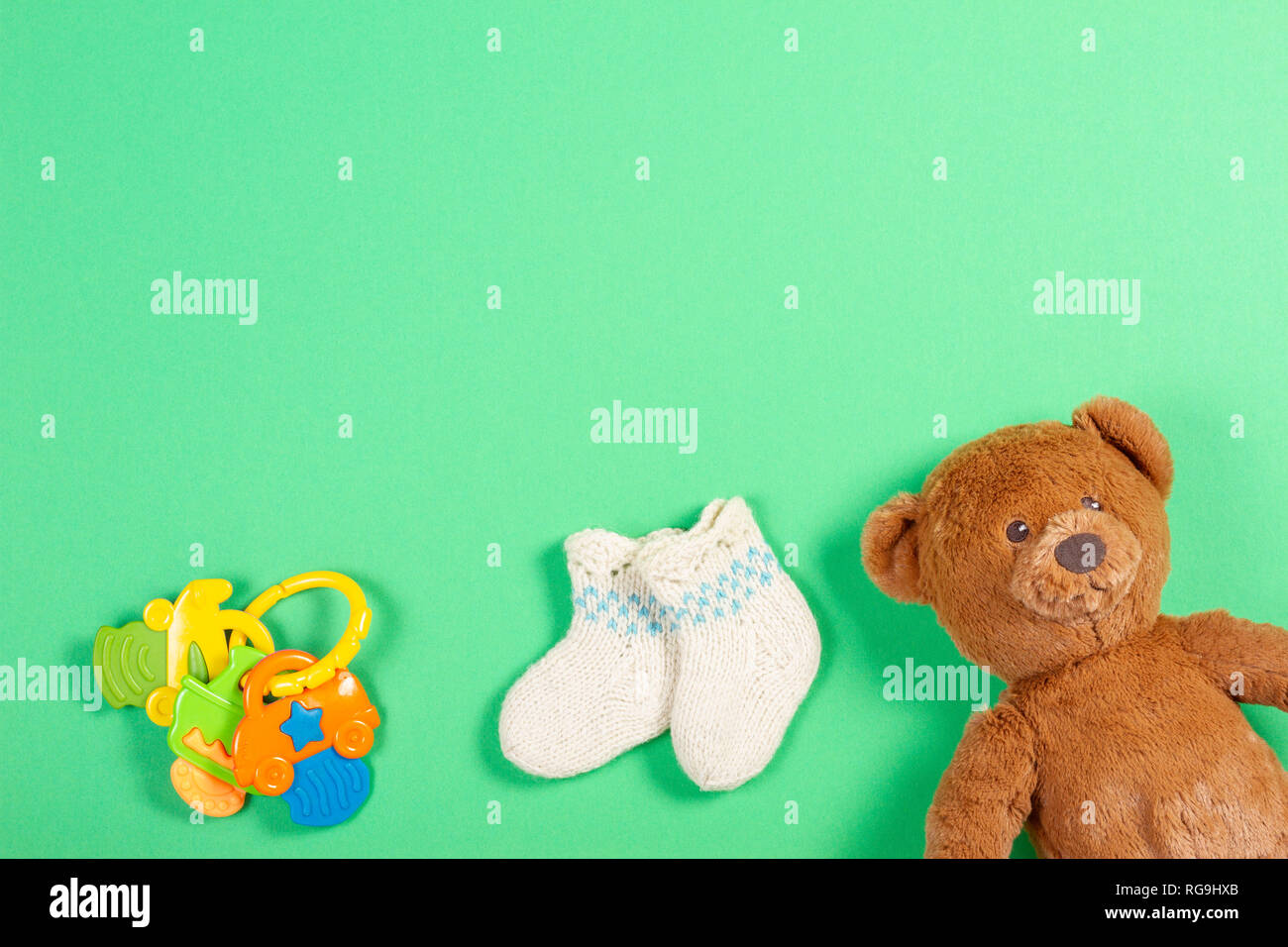 Kids background. White woolen baby socks and teddy bear and toy on