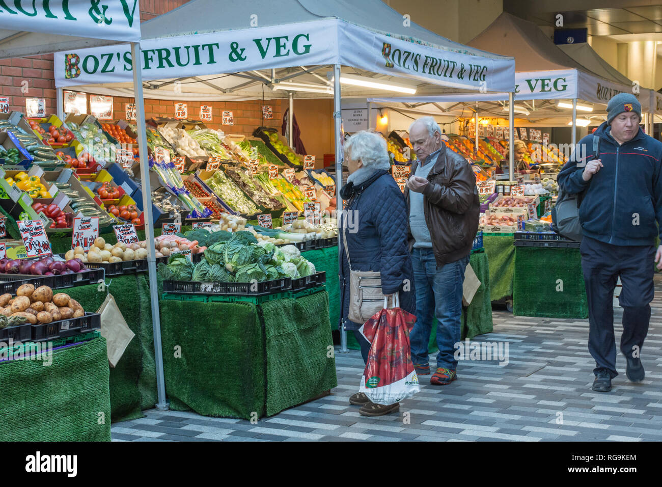 Fruit and vegetable market stall in Market Walk in Woking town centre, Surrey, UK, with people shopping. Everyday life. Stock Photo