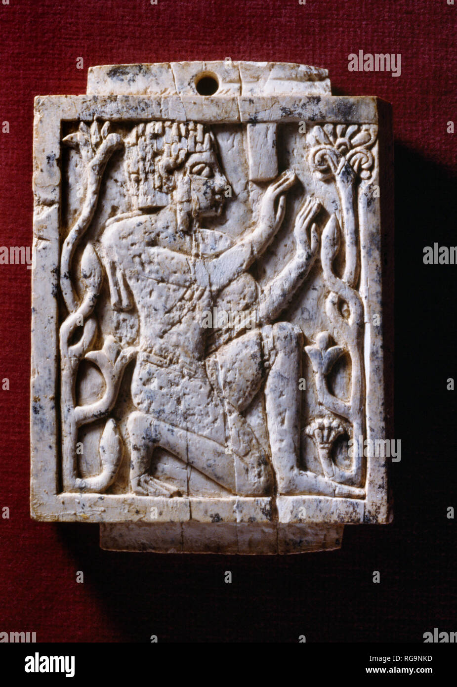 Kneeling male & plant stems: Nimrud Ivory from Room SW11/12 Fort Shalmaneser within the Assyrian city of Nimrud, Iraq, photographed in Bristol Museum. Stock Photo
