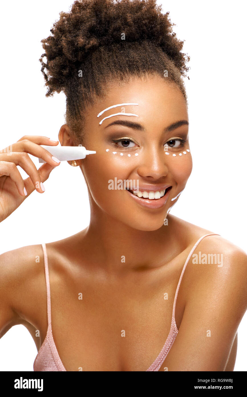 Face lifting. Beautiful smiling woman using  rejuvenating cream. Photo of african american woman with healthy skin on white background. Skin care and  Stock Photo