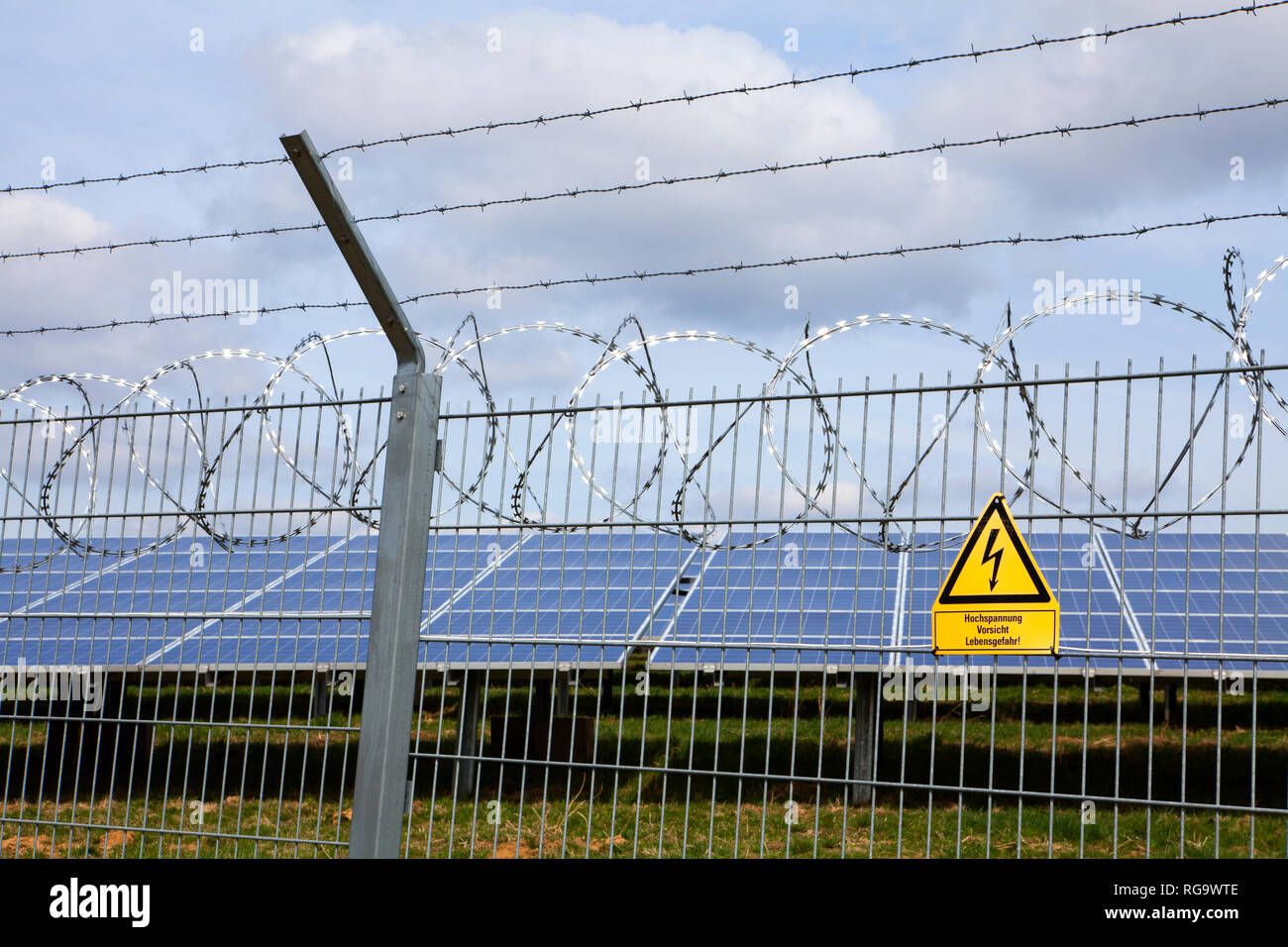 Signpost  and fence at an open space solar photovoltaic plant, Germany, Europe Stock Photo