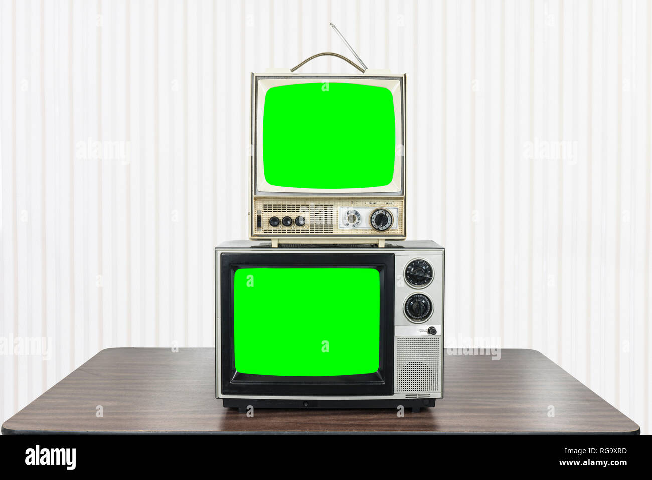 Two vintage television on old table with chroma key green screens. Stock Photo
