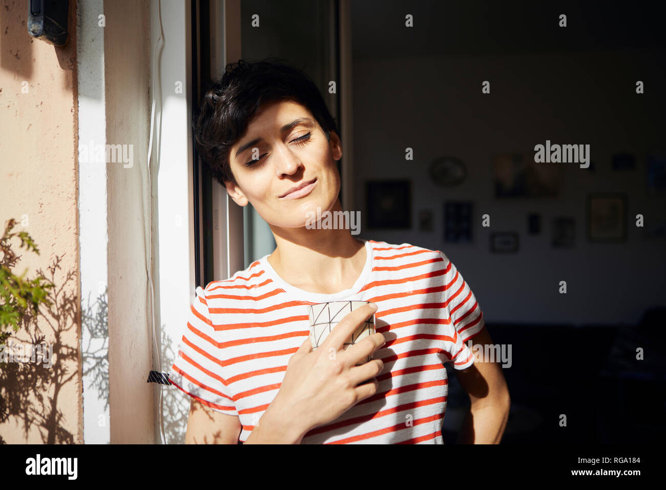 Woman with cup of coffee on balcony enjoying the sunshine Stock Photo