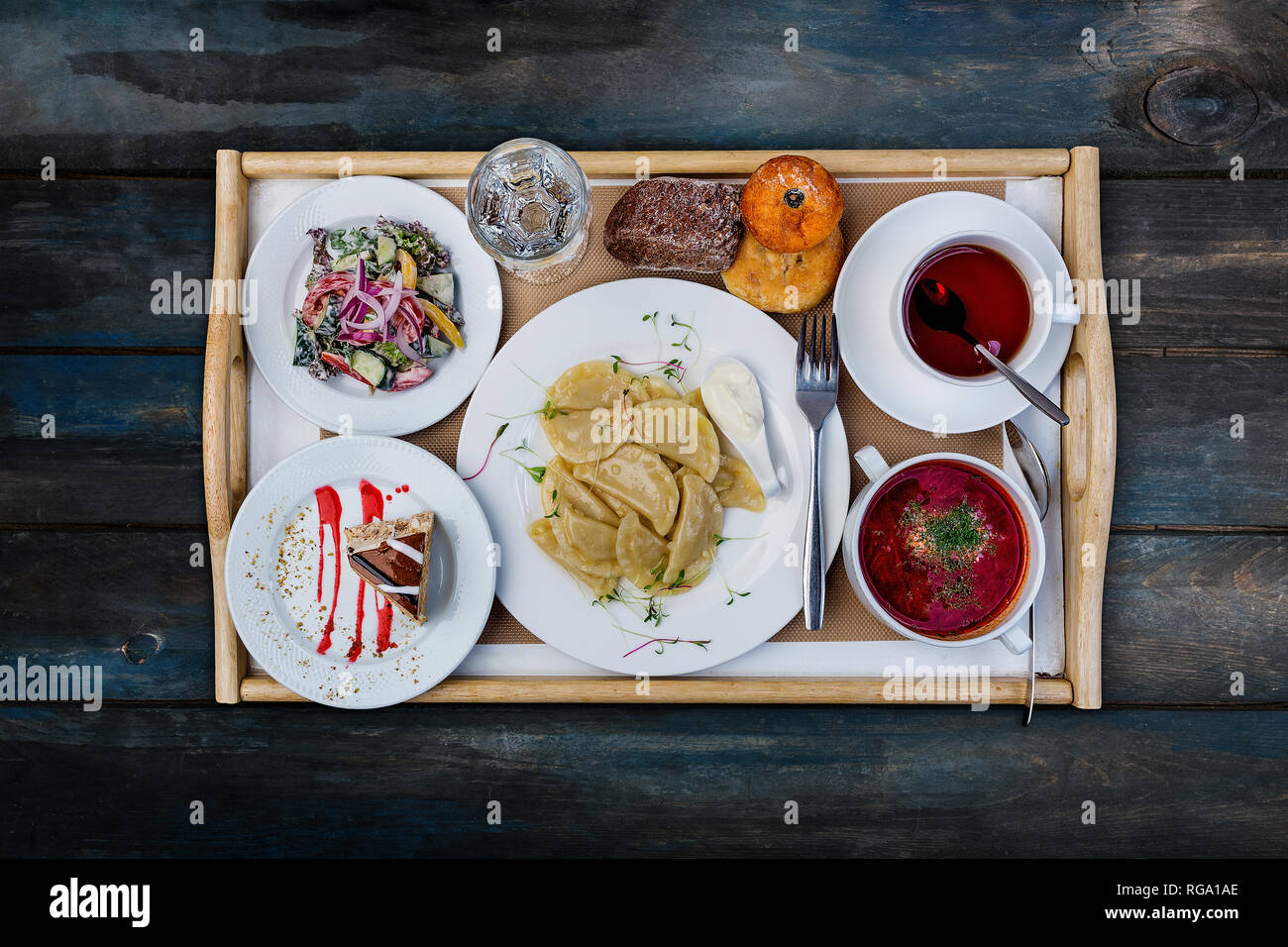 Typical set lunch. Dumplings with potato, borsch and vegetables salad, served with the cutlery. Stock Photo