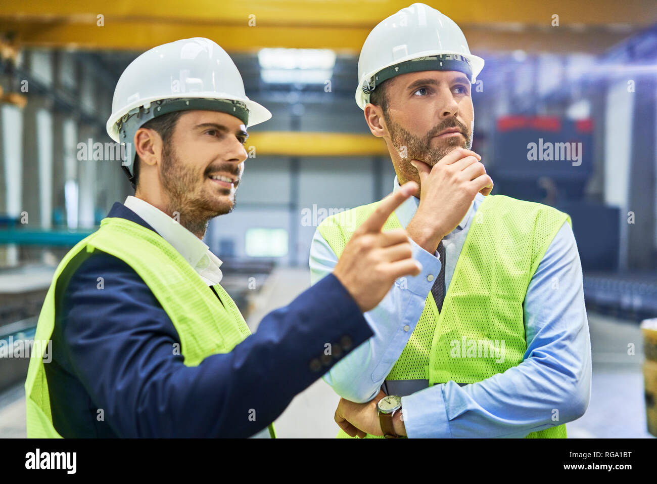 Two managers wearing protective workwear talking in factory Stock Photo
