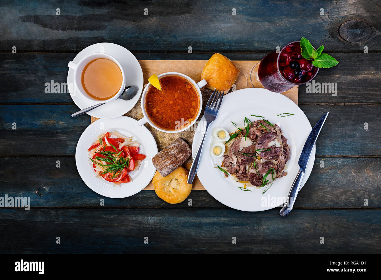 Lunch set. Solyanka, pilaf and tomato salad, served on the tray with the cutlery. Stock Photo