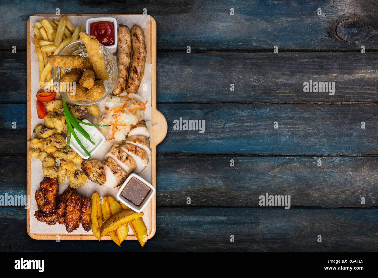 Beer snacks set. Chicken snacks served on cutting board with the wooden background. Top view. Stock Photo