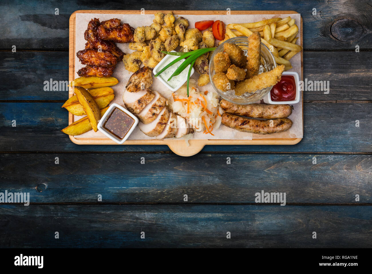 Beer snacks set. Chicken snacks served on cutting board with the wooden background. Top view. Stock Photo
