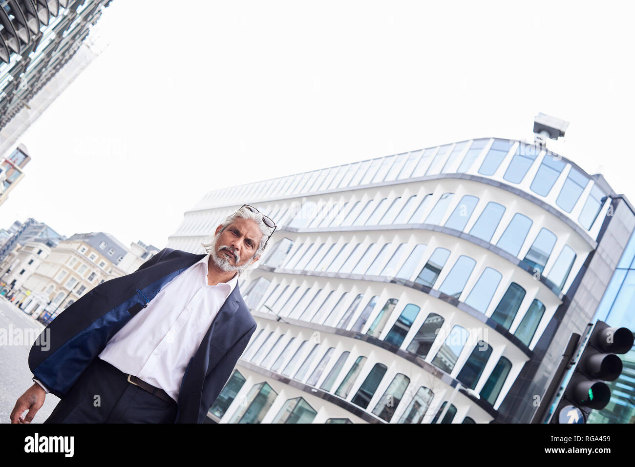 UK, London, portrait of grey-haired senior businessman walking at financial district Stock Photo
