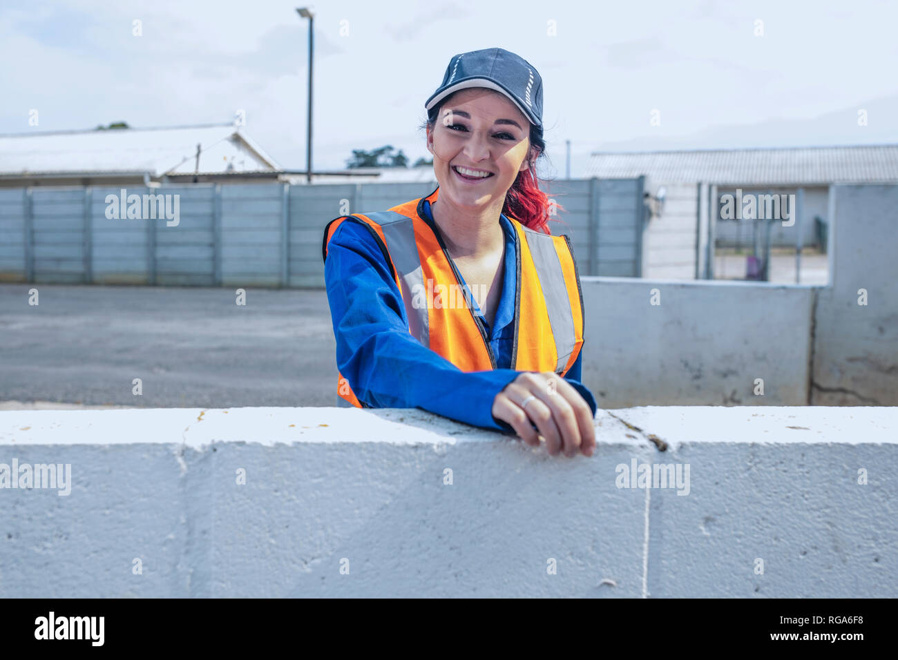 Portrait of smiling young woman wearing overalls and reflective jacket Stock Photo