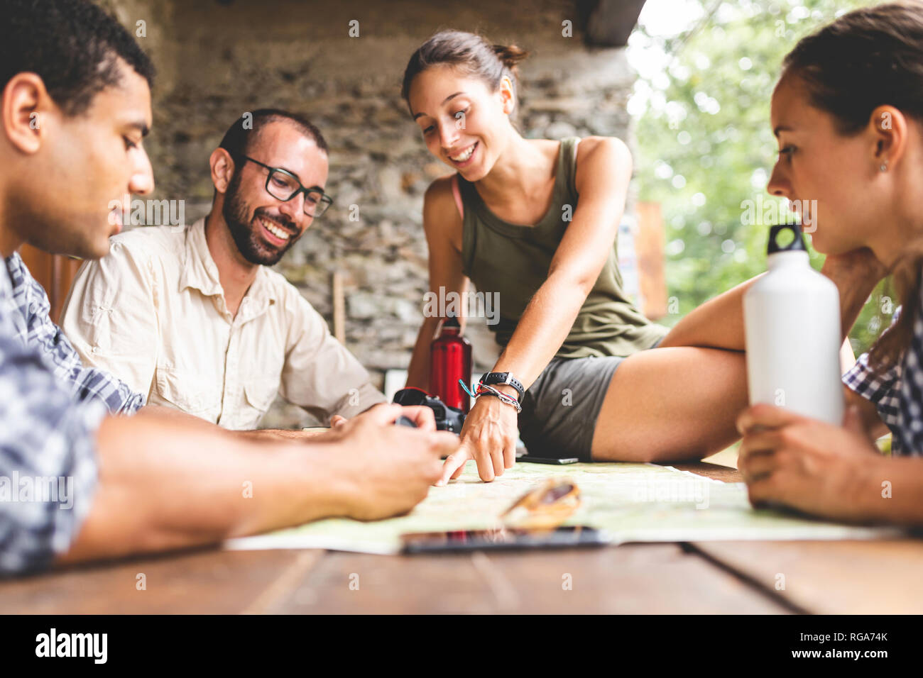 Group of hikers sitting together planning a hiking route looking at map ...
