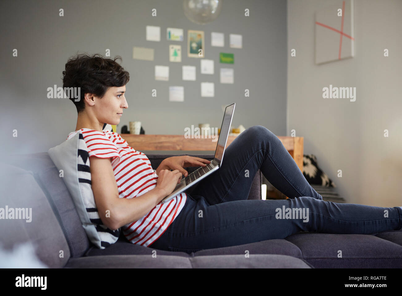Woman using laptop on couch at home Stock Photo