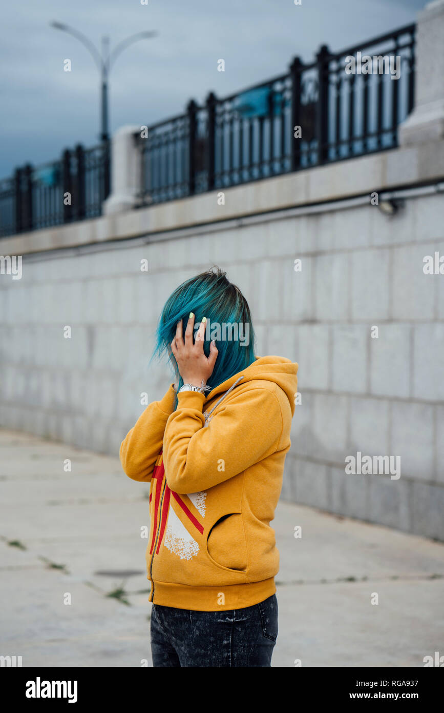 Young woman covering face with her dyed blue hair Stock Photo