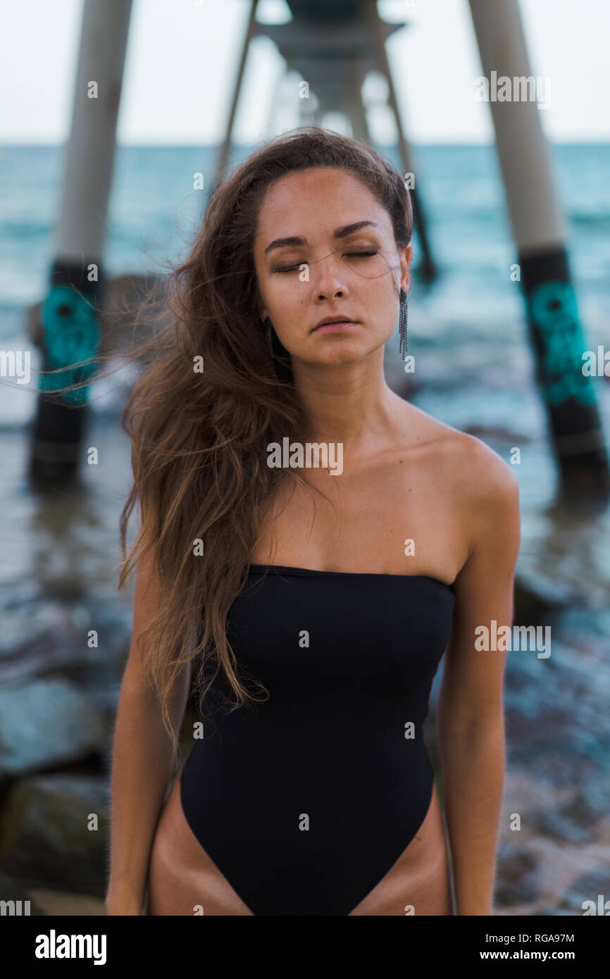 Beautiful young woman with closed eyes wearing swimsuit at the seafront Stock Photo