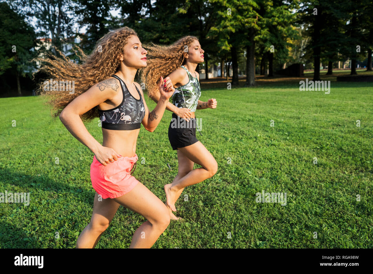 Twin sisters jogging barefoot in a park Stock Photo