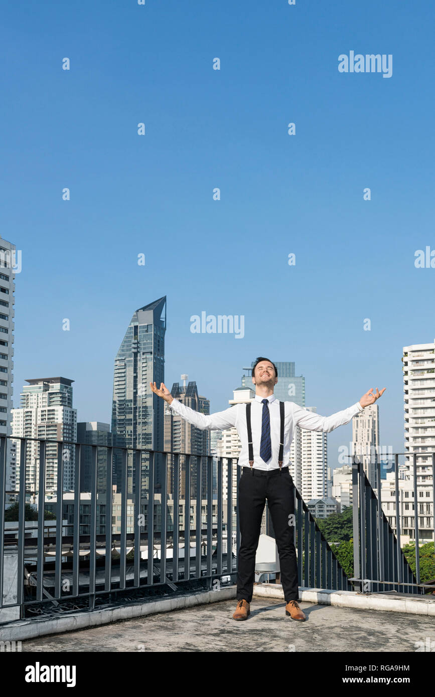 Happy and content successful business man on city rooftop Stock Photo