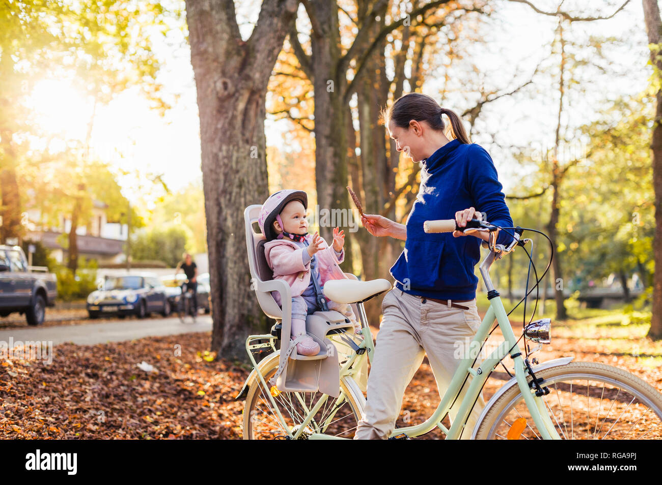 Mother and daughter riding bicycle, baby wearing helmet sitting in ...