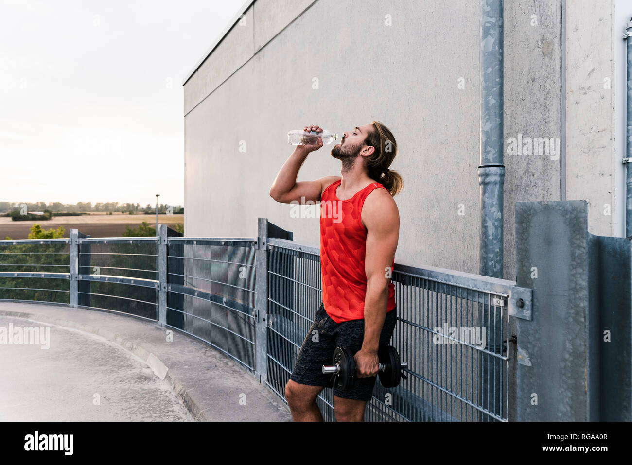 Young man drinking water after training with dumbells Stock Photo