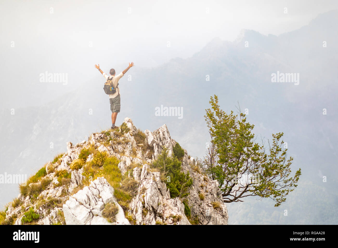 Italy, Massa, man cheering on top of a peak in the Alpi Apuane mountains Stock Photo