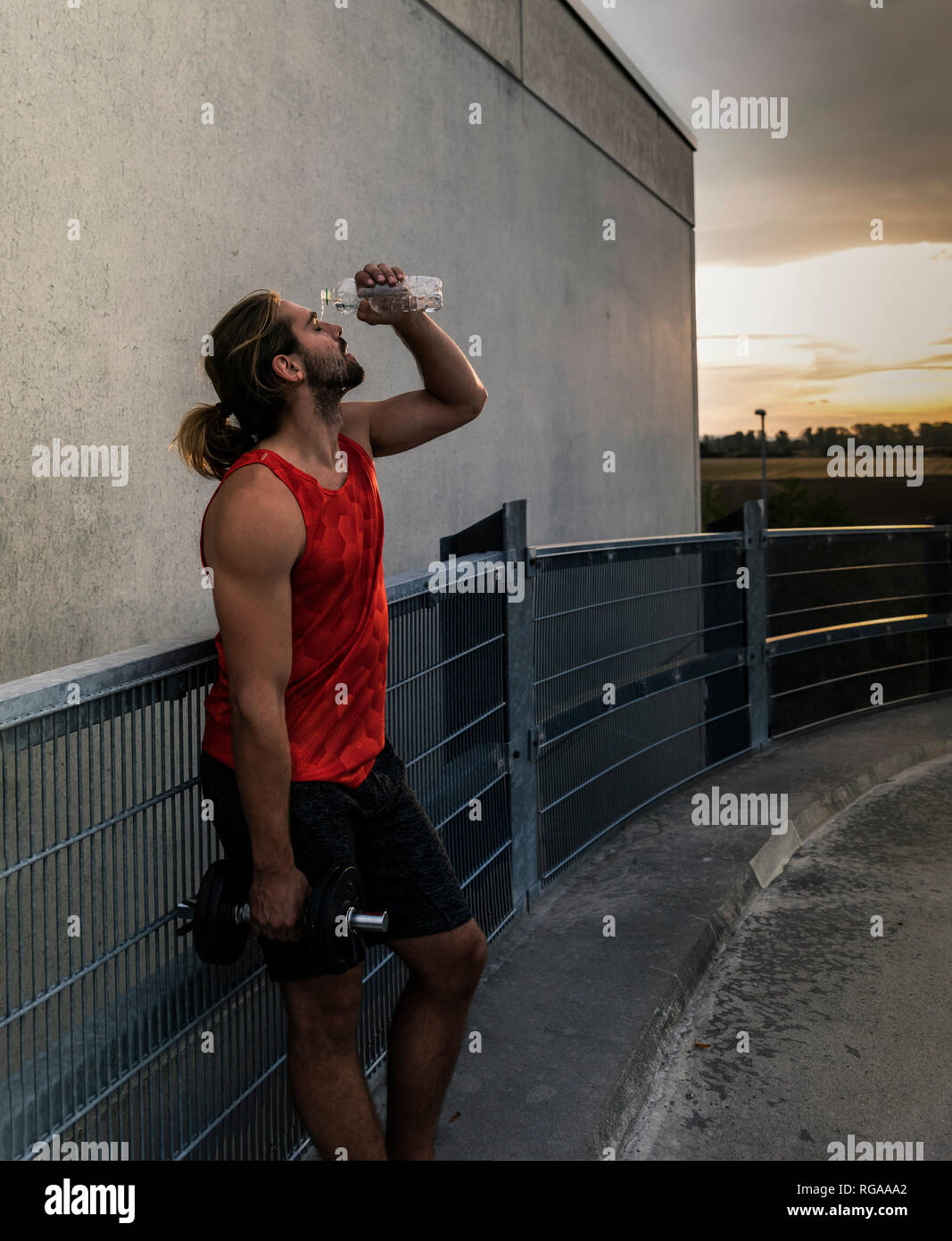 Young man drinking water after training with dumbells Stock Photo