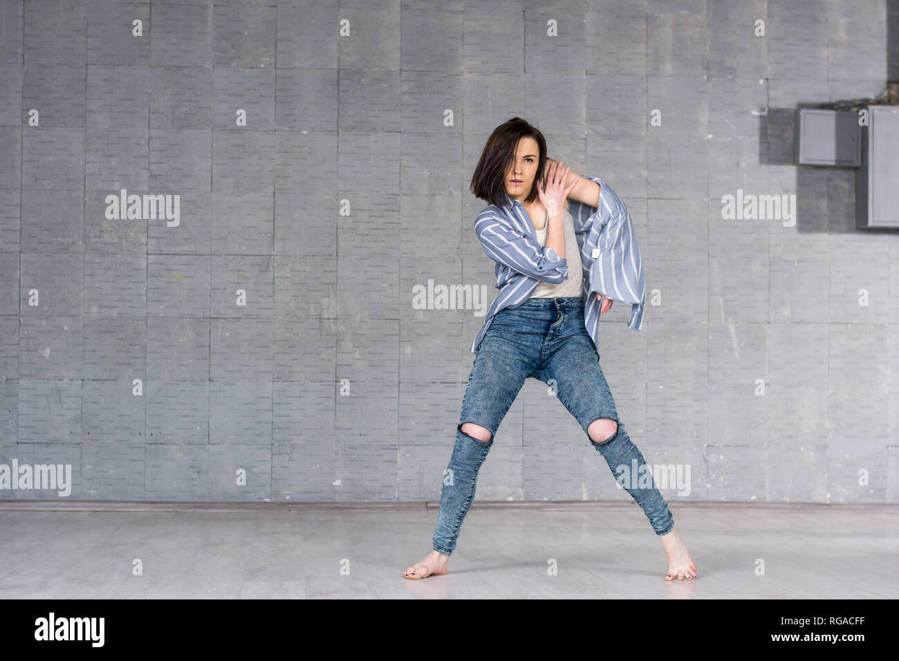 Beautiful girl dancing on studio background. Young slim girl posing on grey wall background. Female talanted dancer. Stock Photo