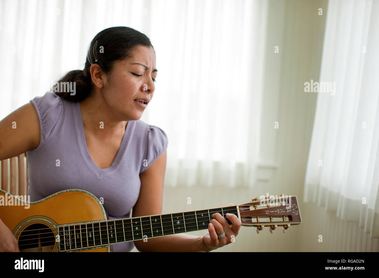 Young woman playing the acoustic guitar and singing Stock Photo - Alamy