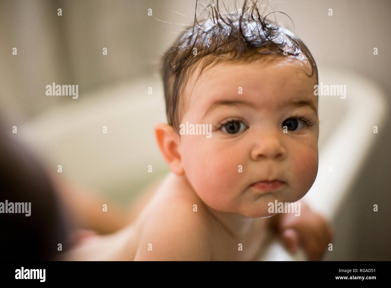 Baby in a bath looks over the tub edge Stock Photo Alamy