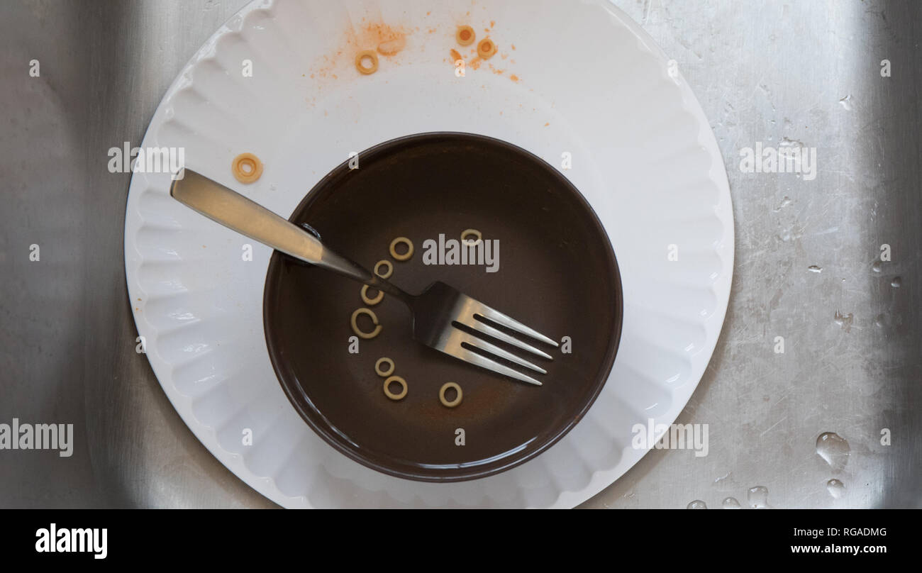 Dirty dishes left in a stainless steel sink. Stock Photo