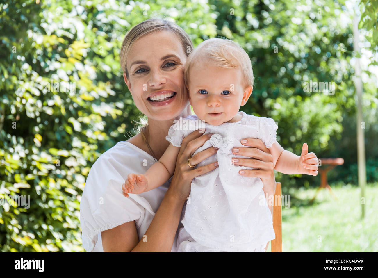 Portrait of happy mother holding her baby girl outdoors Stock Photo