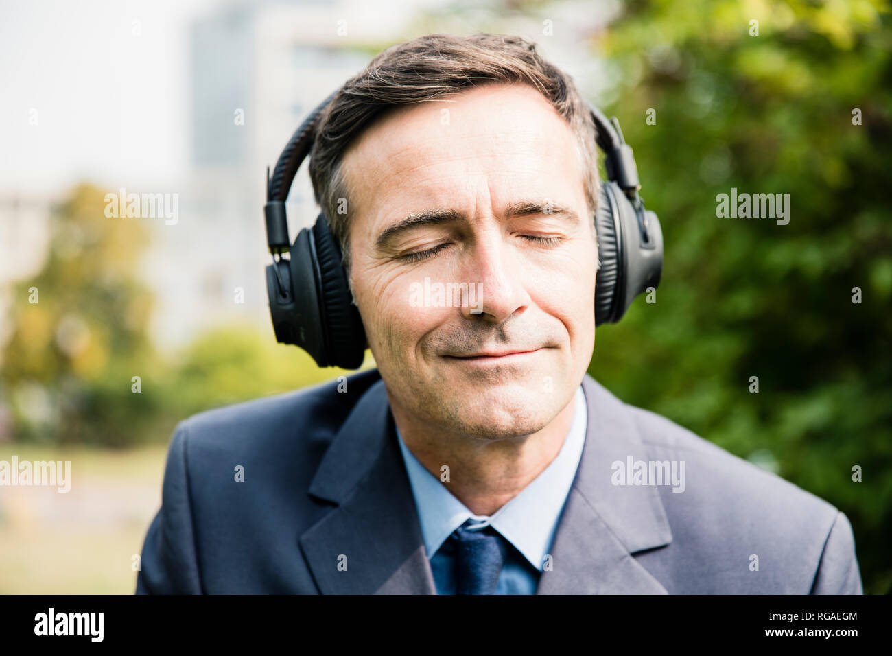 Businessman with closed eyes listening to music with headphones Stock Photo