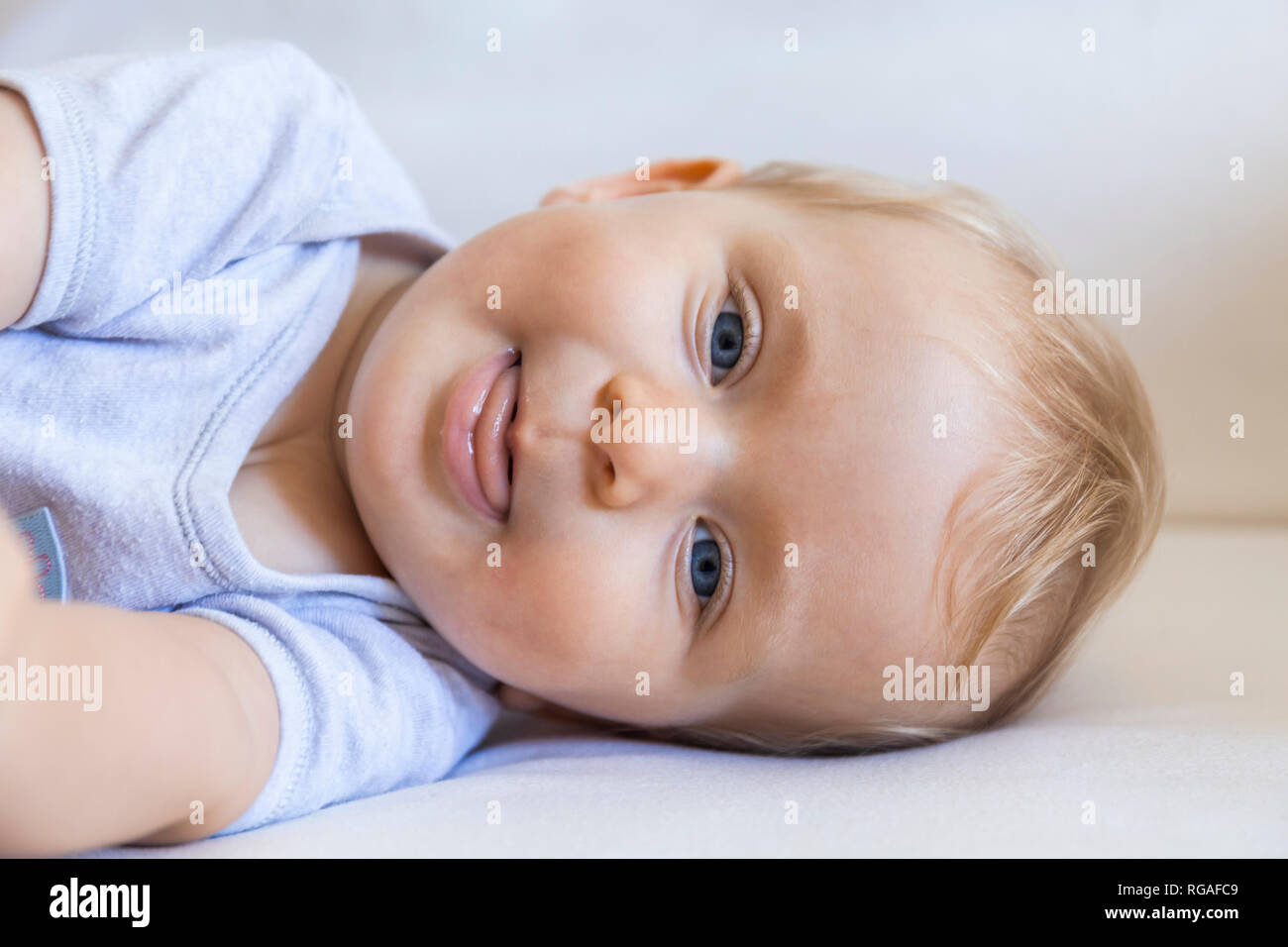 Portrait of blond baby girl lying on couch Stock Photo