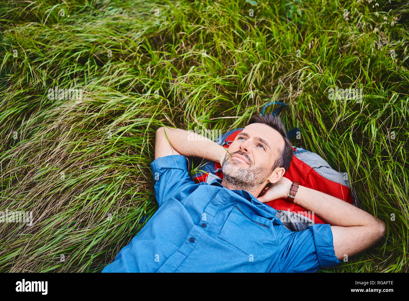 Relaxed man lying in grass enjoying hiking trip Stock Photo