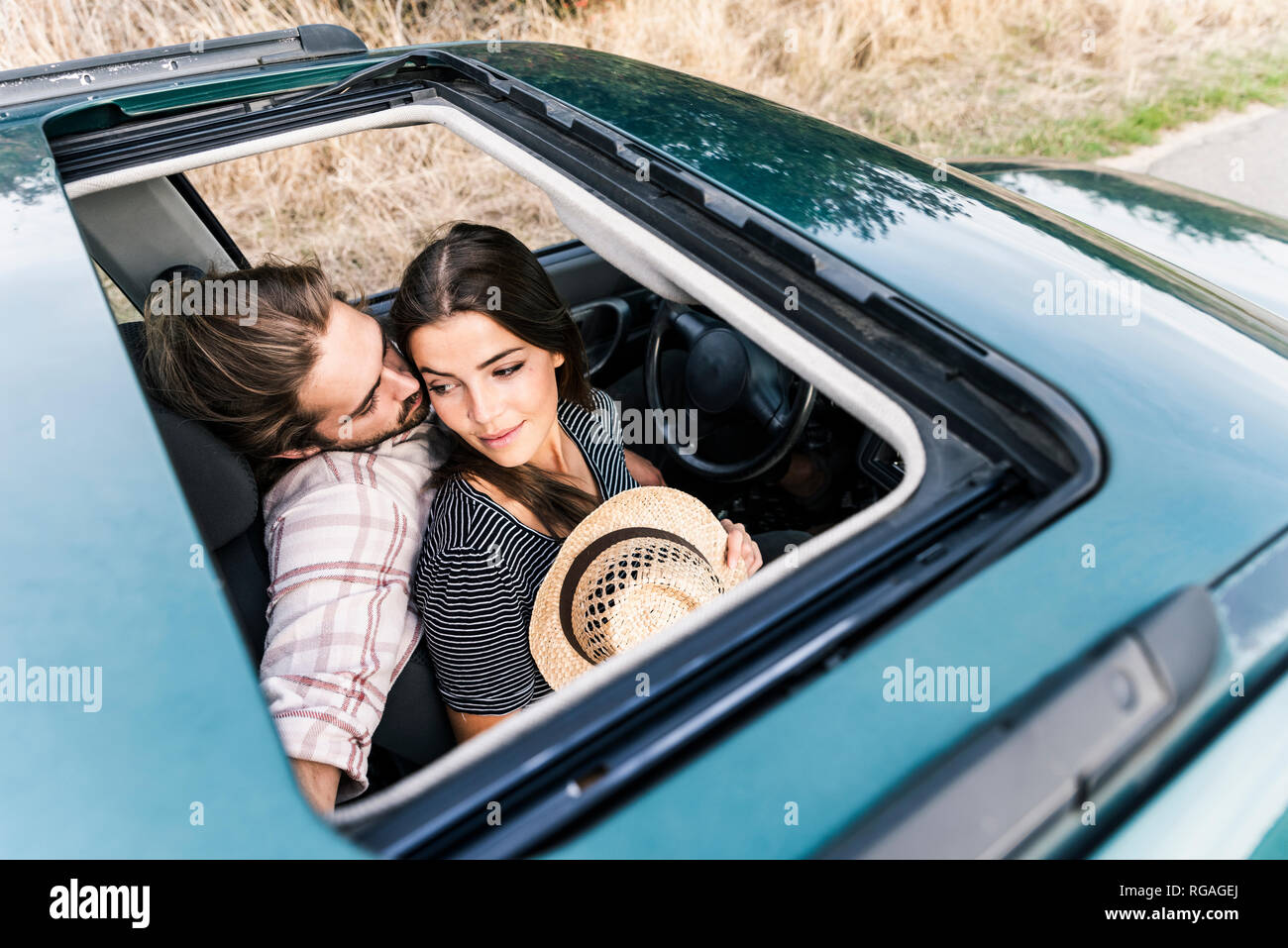 Affectionate young couple in a car seen through sunroof Stock Photo