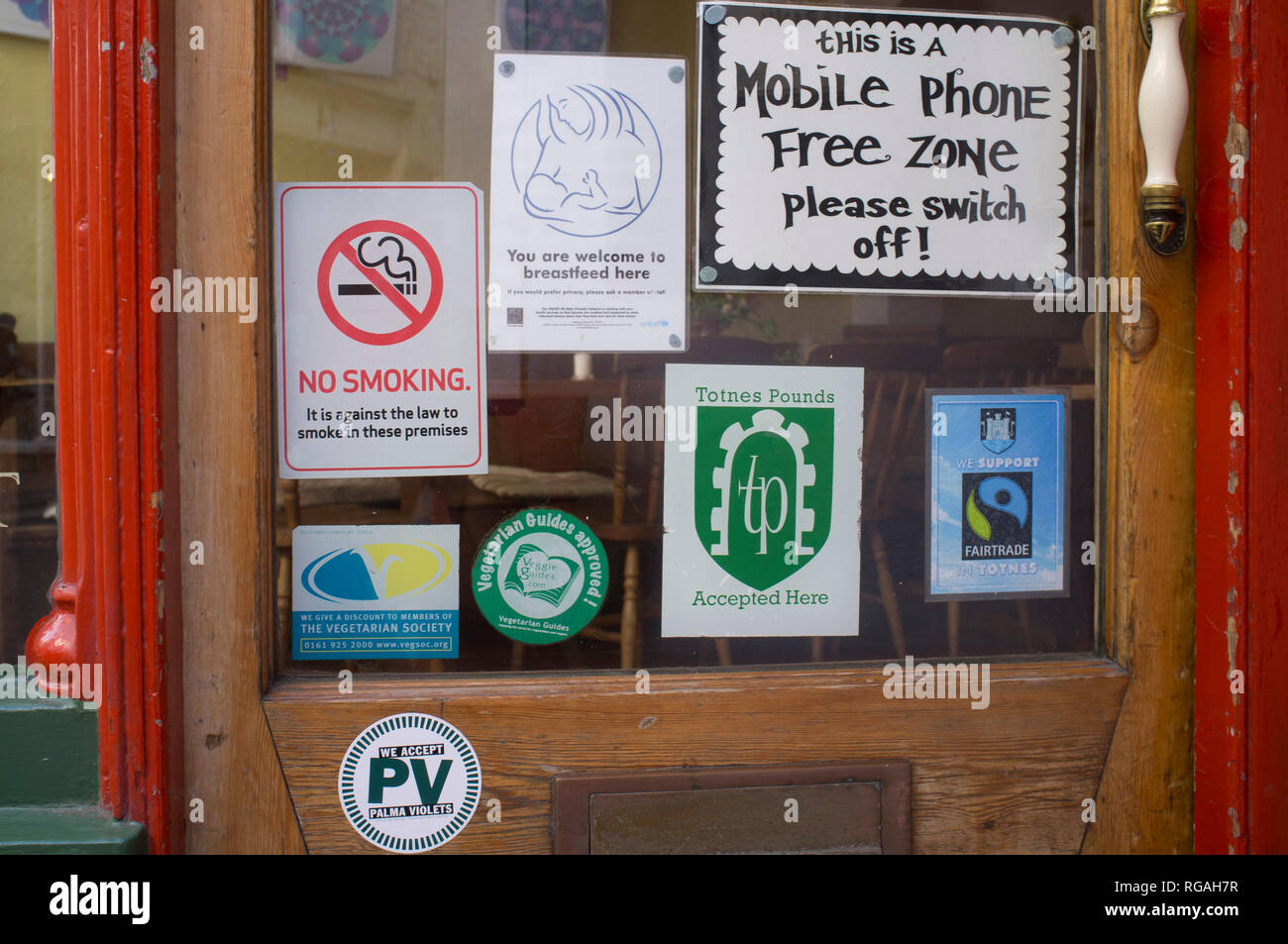 Assorted  signs on the door of an alternative restaurant in Totnes, Devon Stock Photo