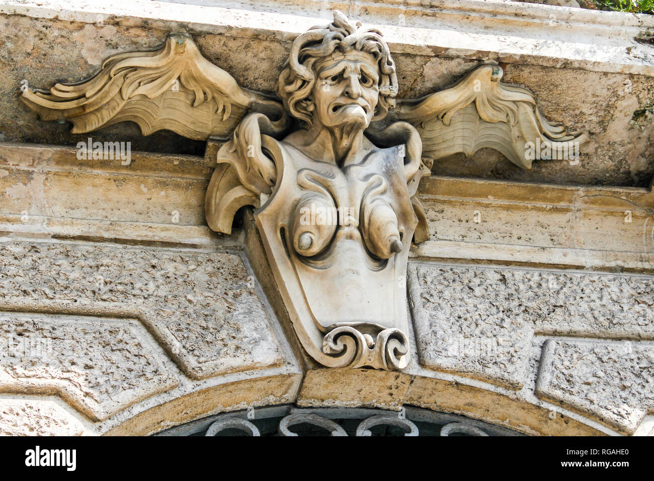 A very ugly and old angel sculpture on a European house, protecting the rich property. Very famous tradition to put guardians on homes Stock Photo