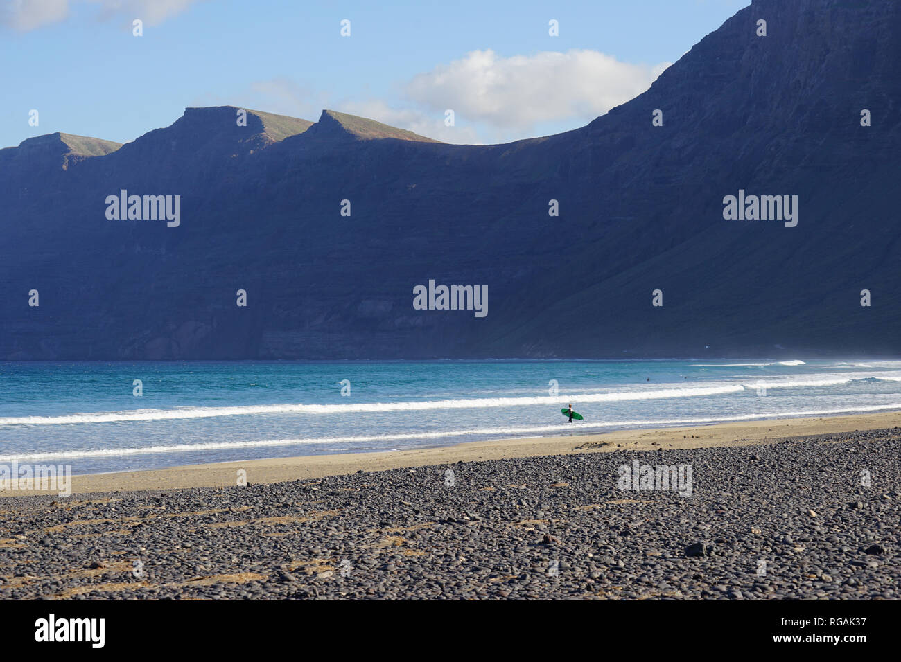 Surfer mit Surfbrett, Playa de Famara, Riscos de Famara, Lanzarote, Kanarische Inseln, Spanien Stock Photo