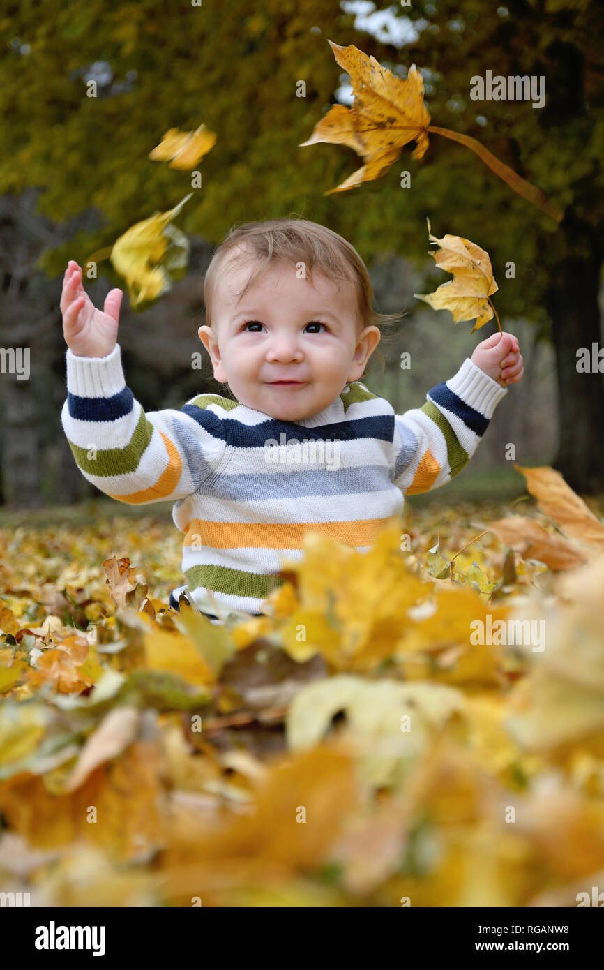 baby boy playing in falling leaves Stock Photo