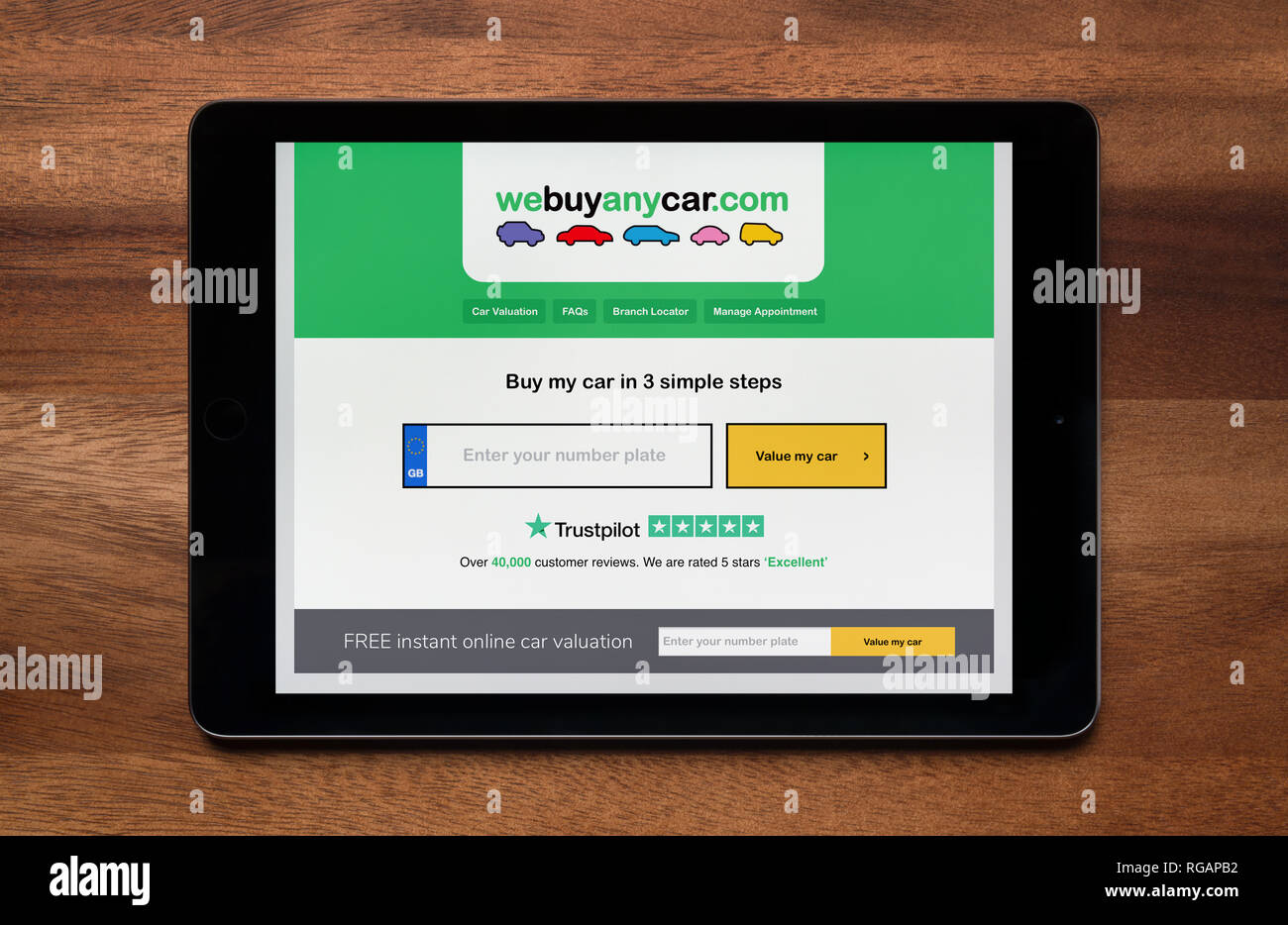 The website of We Buy Any Car is seen on an iPad tablet, which is resting on a wooden table (Editorial use only). Stock Photo