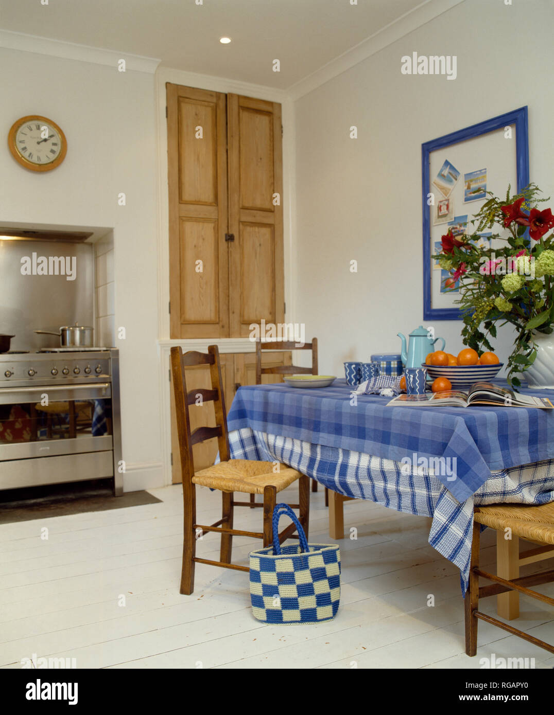 Blue checked cloth on table in kitchen with painted floorboards Stock