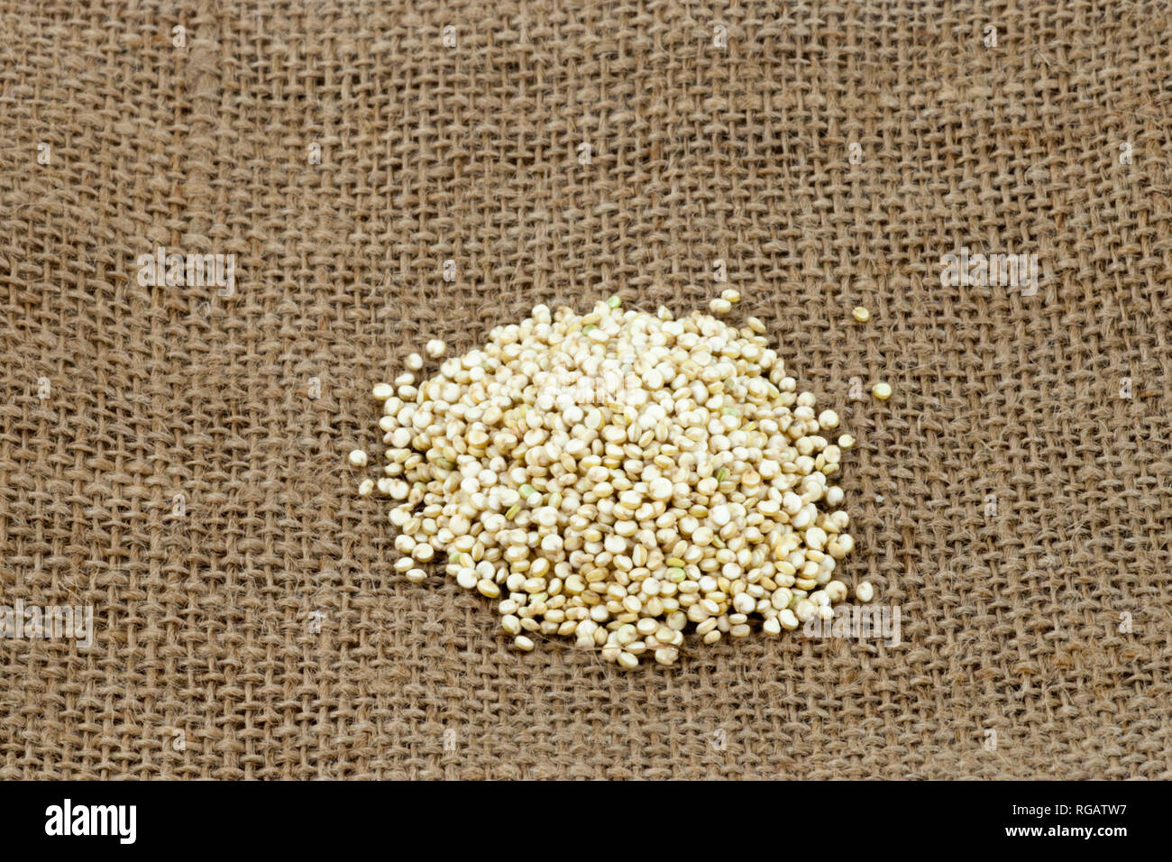 Pile of organic golden (white) quinoa on burlap Stock Photo