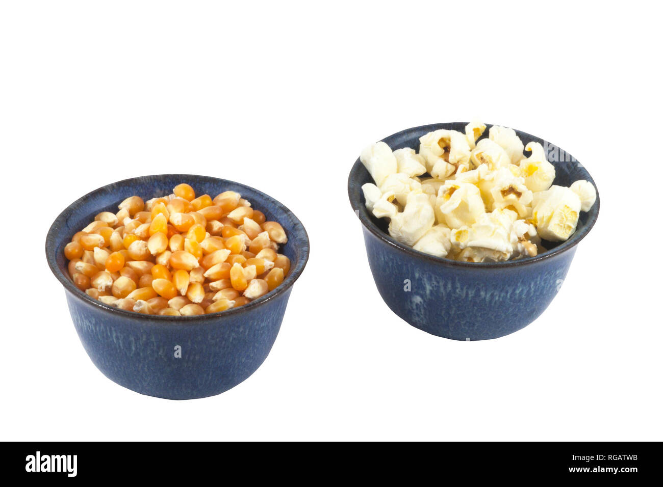 Bowls of unpopped and popped organic popcorn on a white background