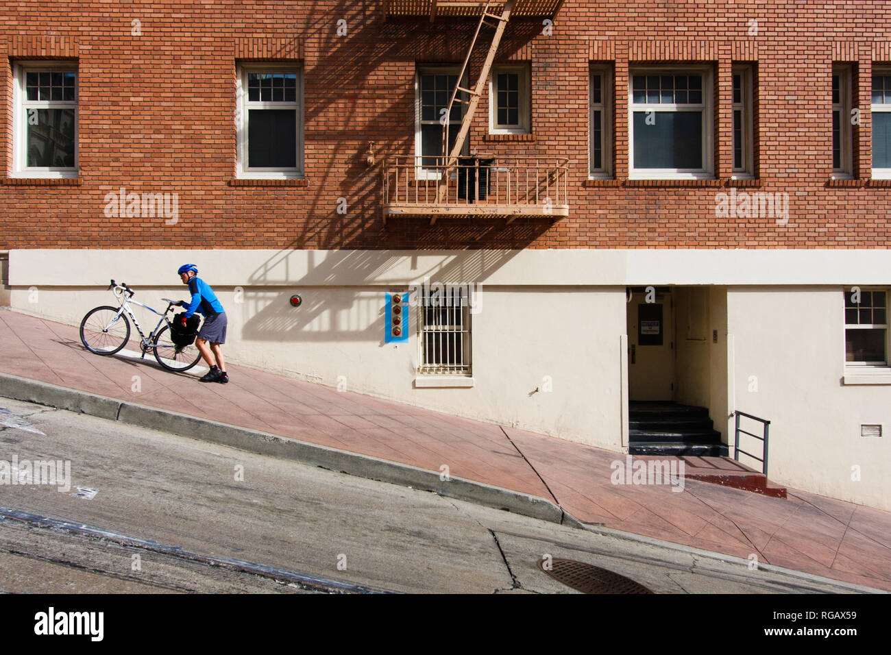 cyclist pushing a bike up a steep hill Stock Photo