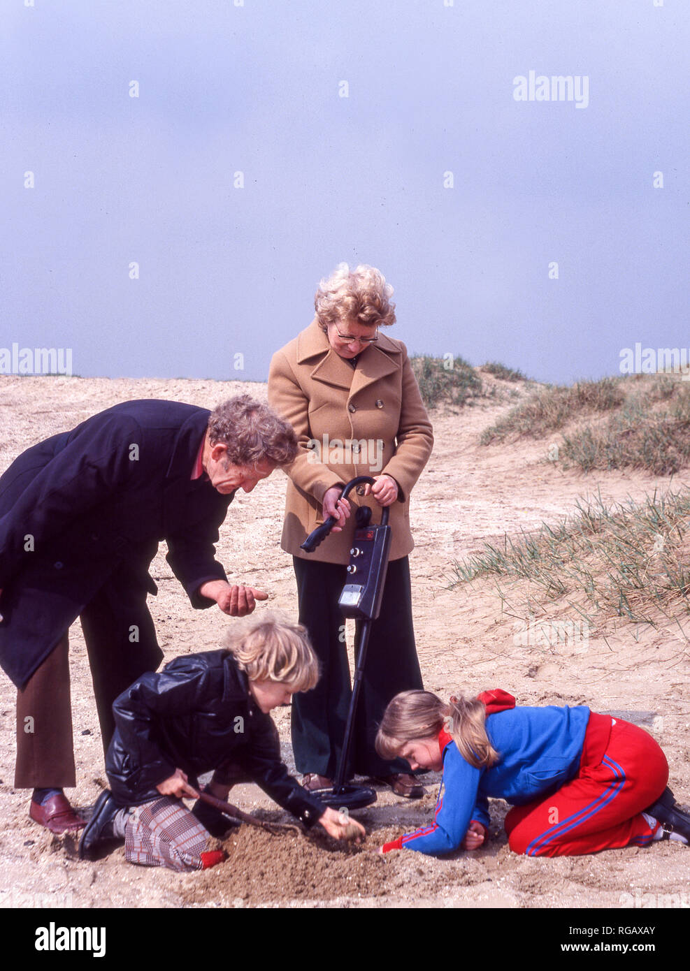 Grandparents with two grandchildren using a metal detector on a beach in northwest England. Stock Photo