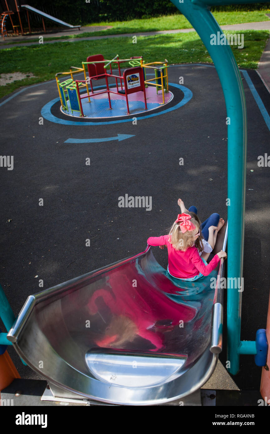 two caucasion girls on a slide in a playground Stock Photo - Alamy