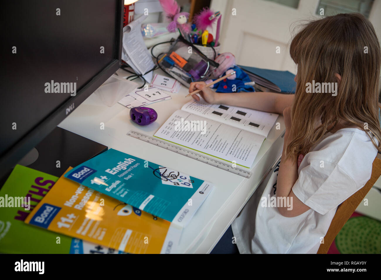Young girl doing her maths homeowrk at her desk Stock Photo