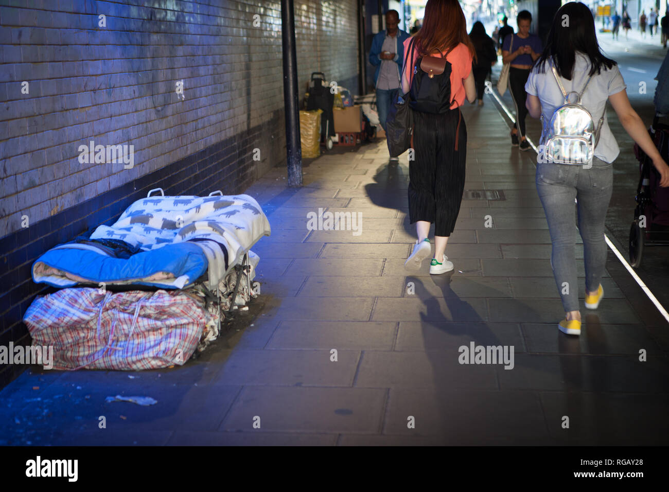 2 girls ignoring walking past homeless in Fisbury Park London Stock Photo