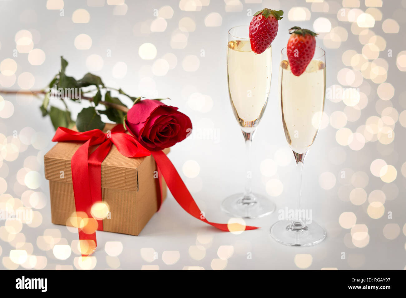 two champagne glasses and gift with red rose Stock Photo - Alamy