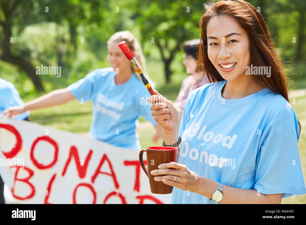 Young volunteer volunteer with paint and brush in front of the Donate Blood poster Stock Photo