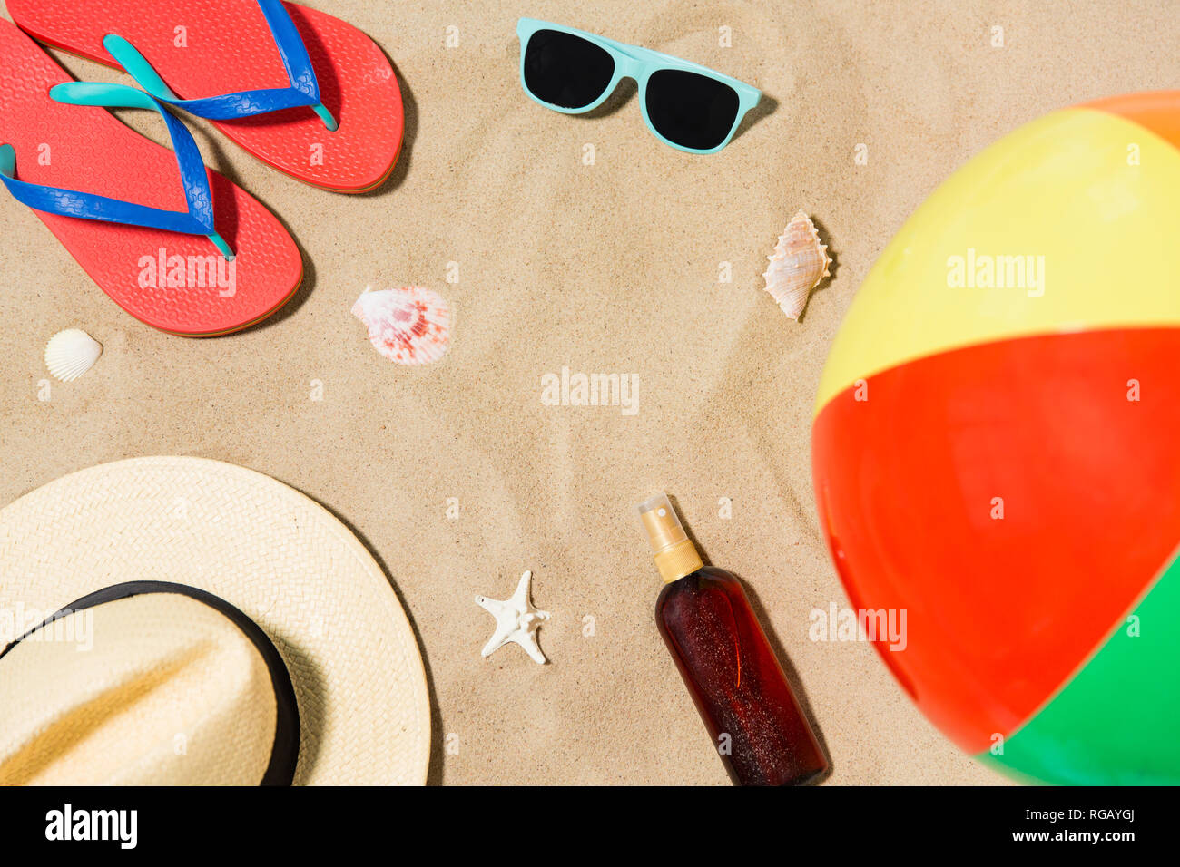 hat, flip flops and shades and beach ball on sand Stock Photo - Alamy